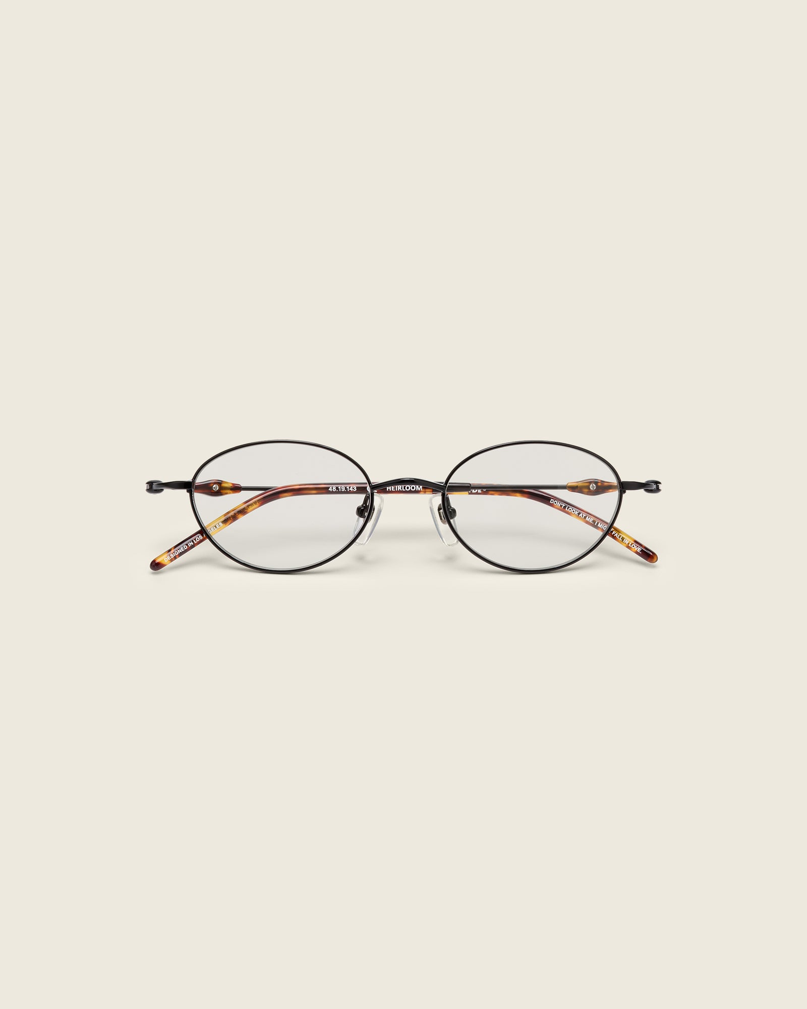 Slim, oval black titanium frames with adjustable nose pads and lightweight acetate arm temple. Face view.