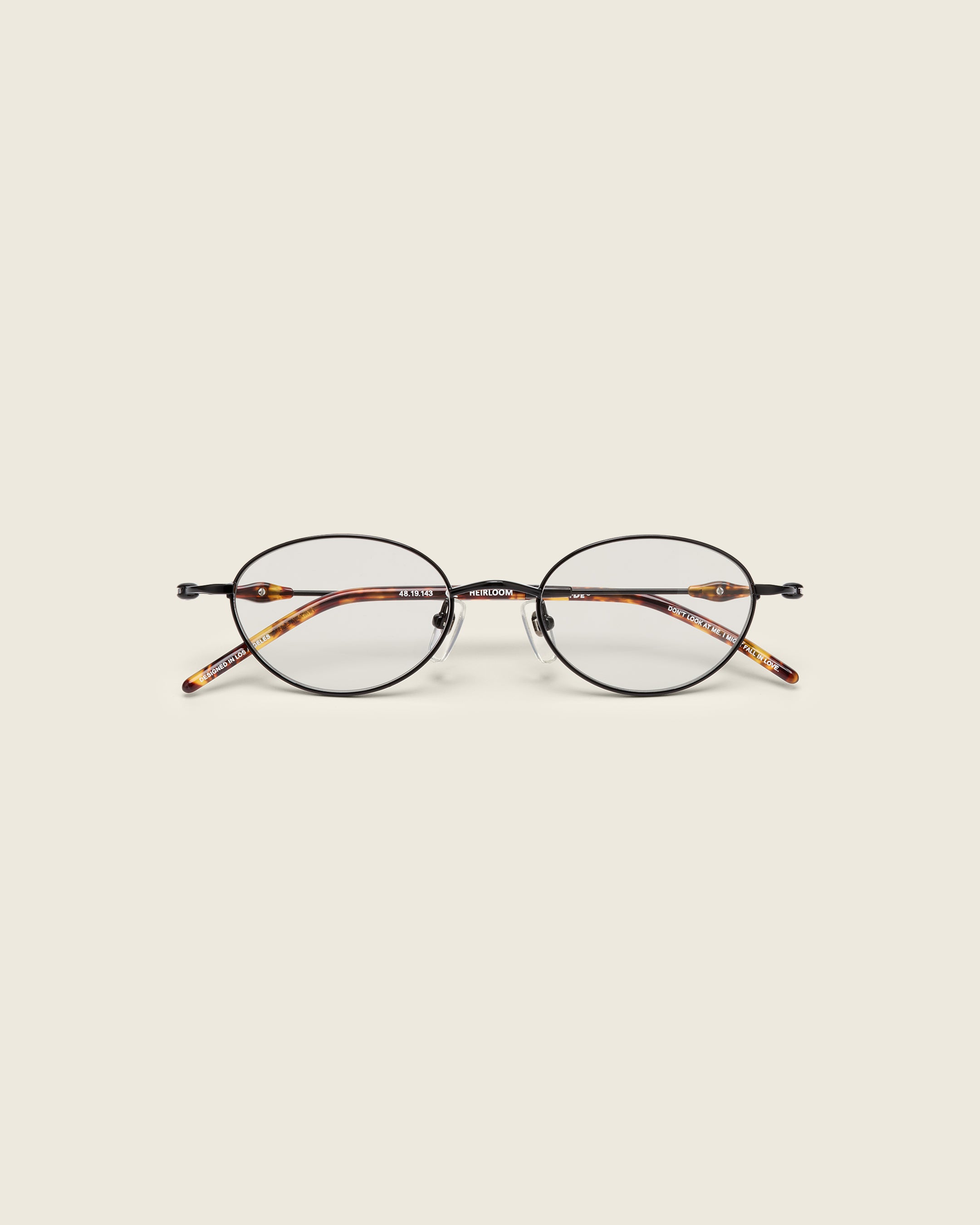 Slim, oval black titanium frames with adjustable nose pads and lightweight acetate arm temple. Face view.