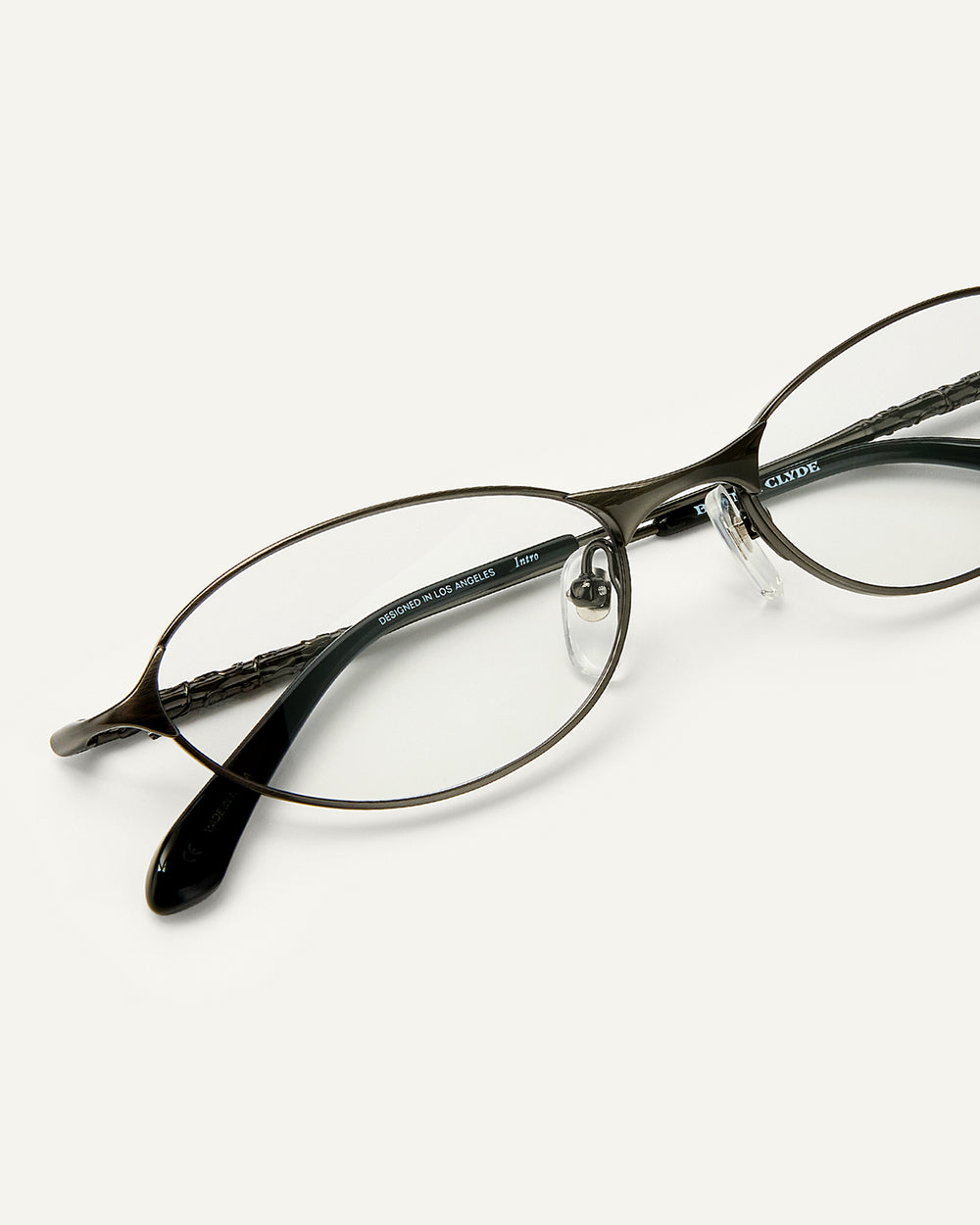Close up shot of Bonnie Clyde Intro eyeglasses in gunmetal titanium frames with black acetate details and clear lenses.