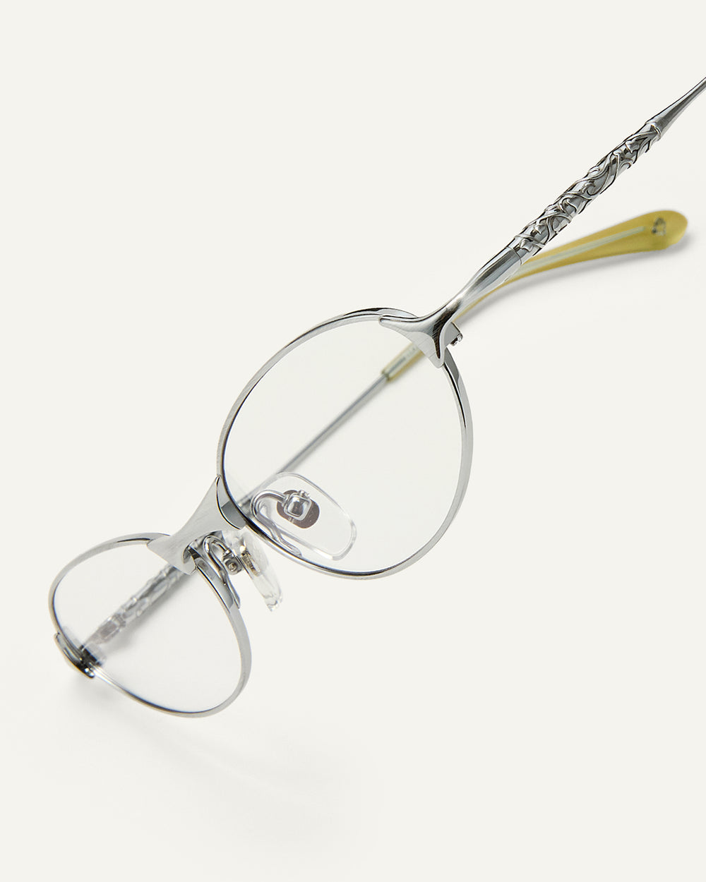 Side shot of Bonnie Clyde Intro eyeglasses in silver titanium frames with green acetate details and clear lenses.