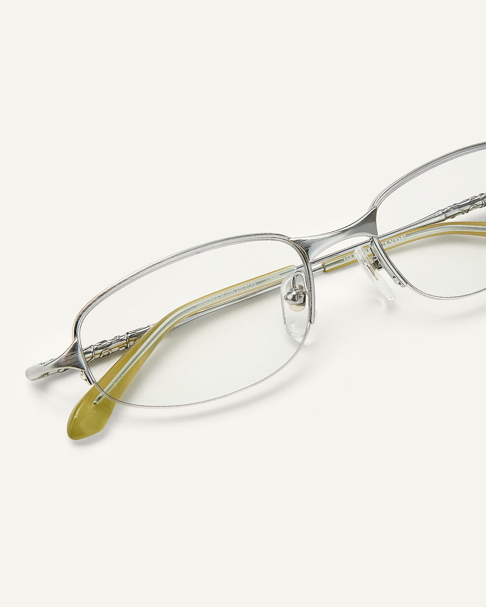 Close up shot of Bonnie Clyde Outro eyeglasses in silver titanium frames with green acetate details and clear lenses.
