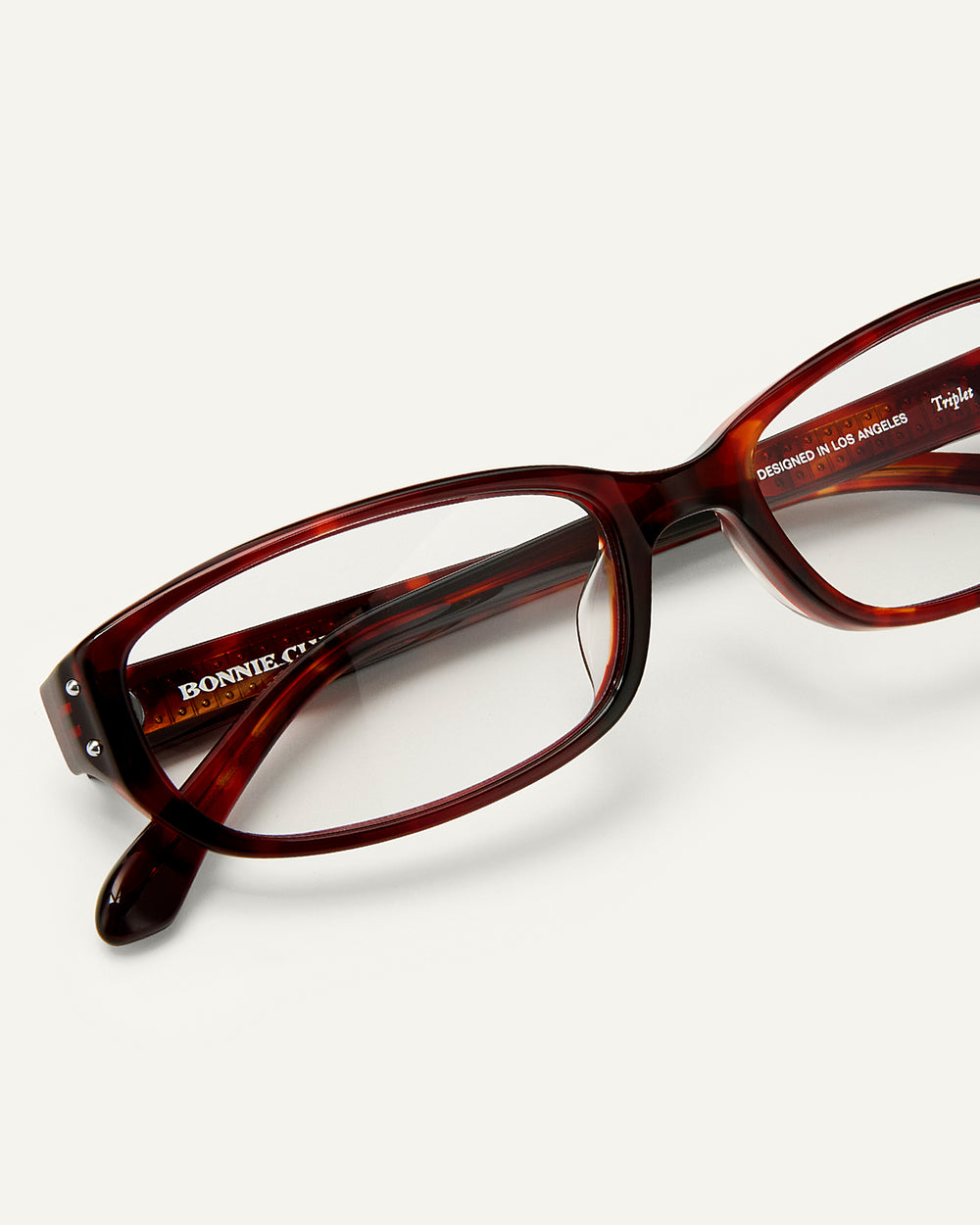 Close up shot of Bonnie Clyde Triplet eyeglasses in red tortoise frames with clear lenses.